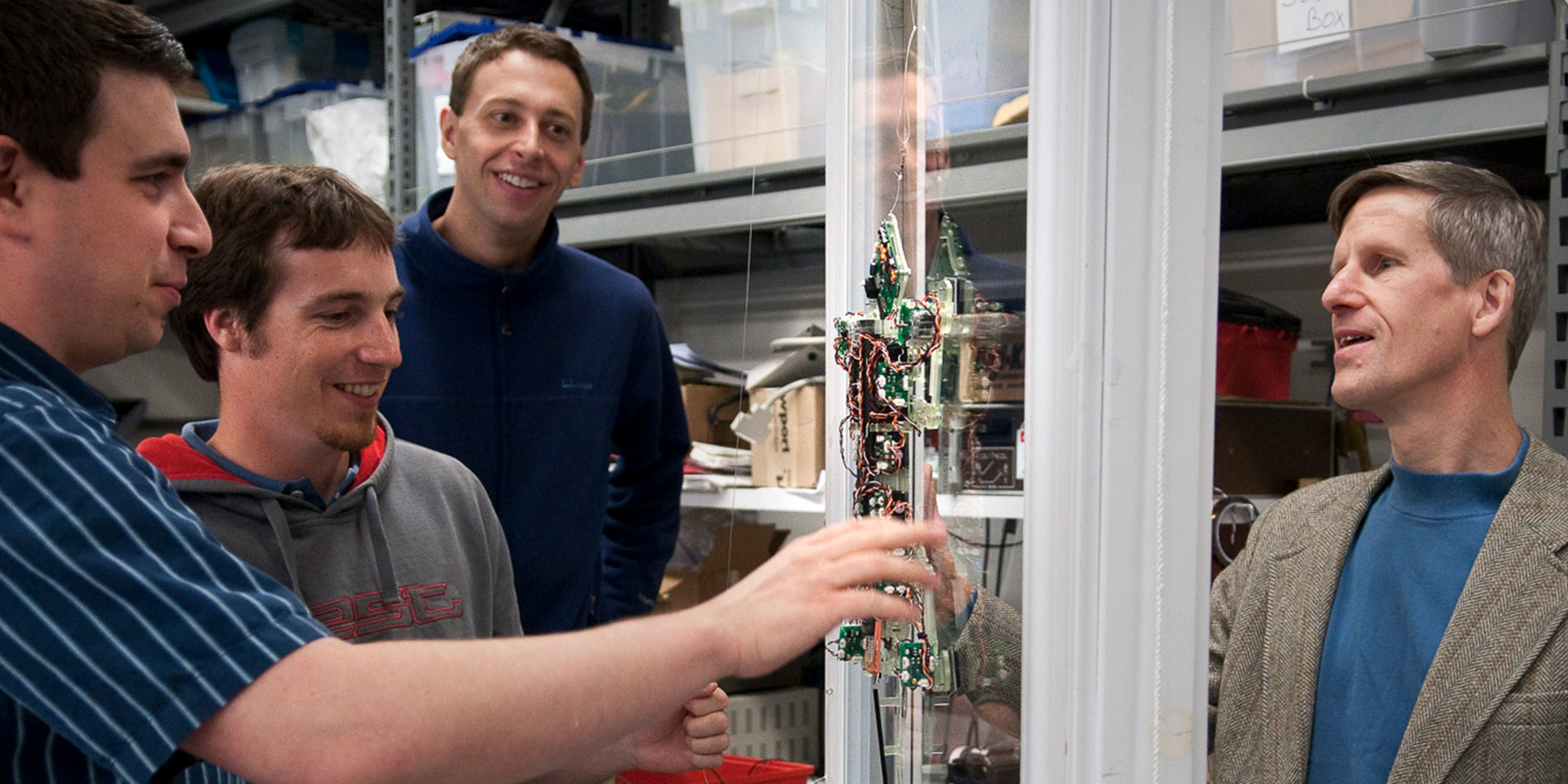 
Salomon Trujillo, John Ulmen, Alan Asbeck, and Cutkosky observe the Stickybot III in a trial run on a glass surface. | Photo credit: L.A. Cicero