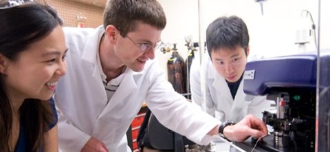 Three lab workers looking at machine