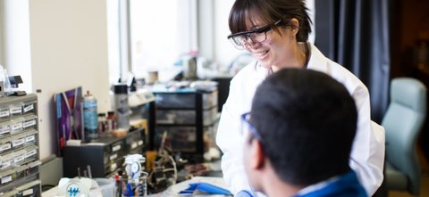 Two students with lab goggles looking at each other